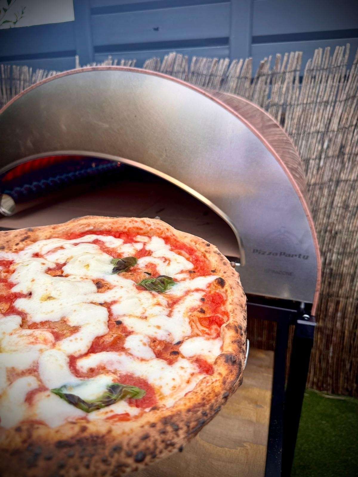 Front view of a large antique copper Pizza Party Inspirational oven, with an open door and pizza stone baking surface