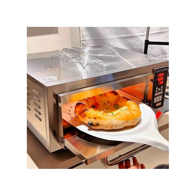 Een pizza halen uit de Tentation MAX elektrische oven met een pizzaschep, zichtbare spiegelpoets roestvrijstalen binnenkamer