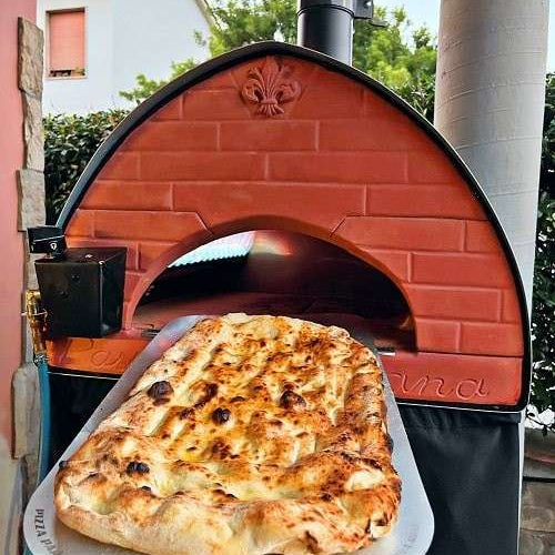 Vers gebakken pizza op een schovel voor de oven, Pizza Party Bollore, Passione Toscana op het terras