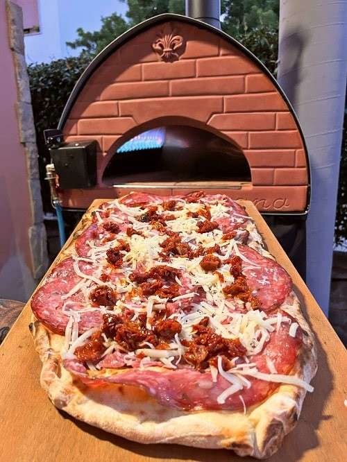 Pizza gebakken in de Pizza Party Passione hybride hout- en gasoven met salami en gedroogde tomaten
