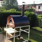 four à bois Pizza Party Pizzone noir sur support à roues en aluminium argenté, vue latérale en jardin