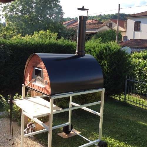 Wood-fired Pizza Party large black pizza oven on a stand with silver aluminum wheels, side garden view