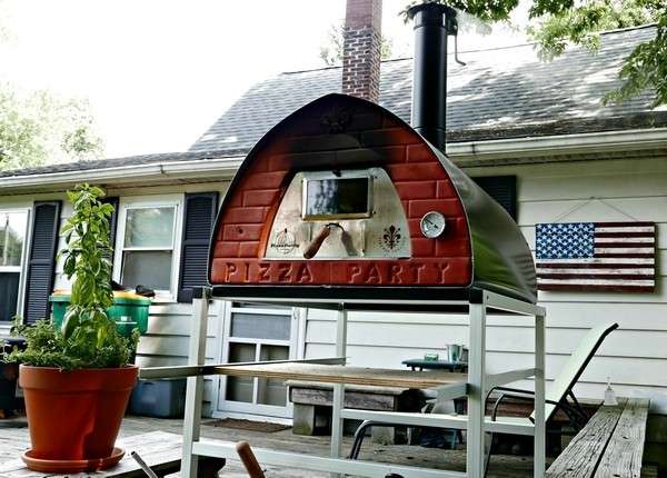 Wood-fired Pizza Party Pizzone oven on aluminum-wheeled stand on an American terrace with a US flag
