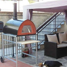 Four à bois Pizza Party Pizzone sur support à roulettes en aluminium sur la terrasse avec un chien