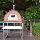 Wood-fired Pizza Party 70x70 oven on a stand with silver aluminum wheels under a pergola