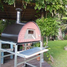 Black wood-fired Pizza Party Bollore pizza oven on a stand with aluminum wheels under a pergola